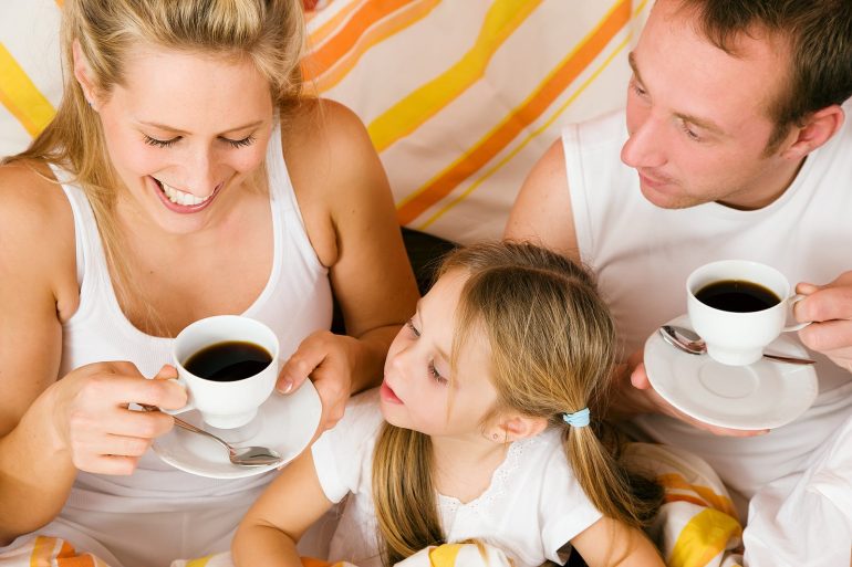family drinking coffee in bed
