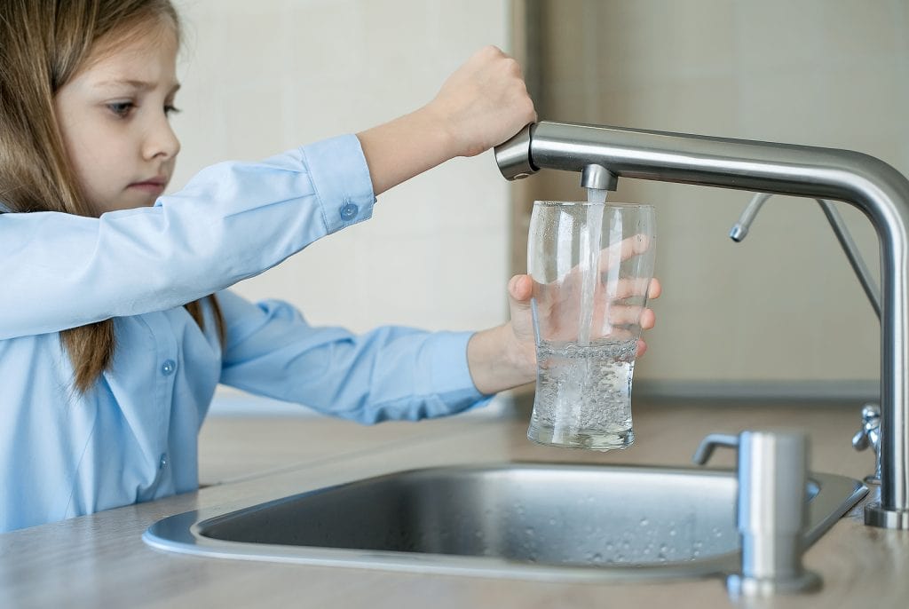 Child filling glass of water full of sediment