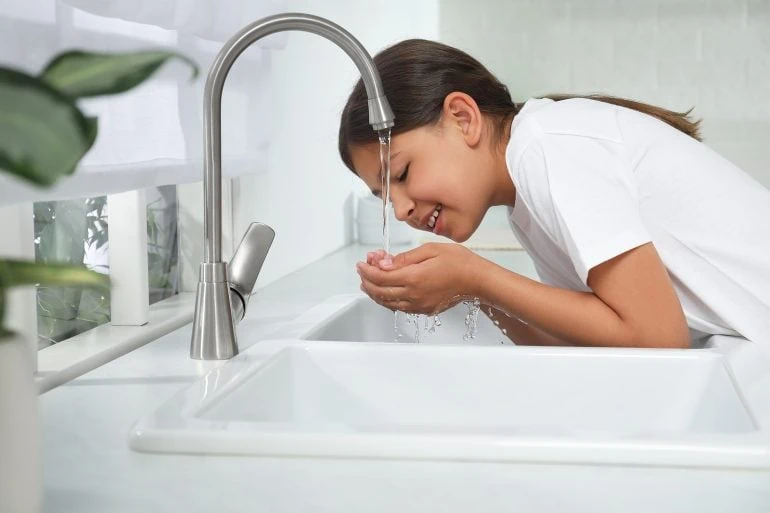 girl drinking water from sink