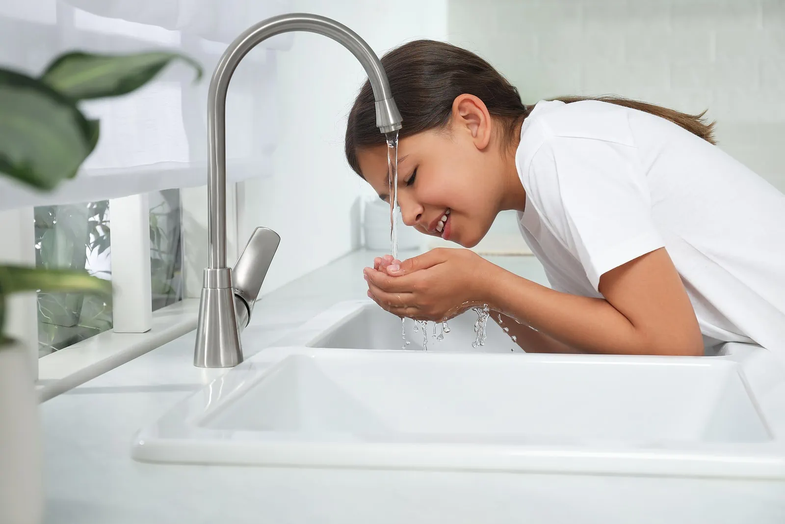 girl drinking water from sink