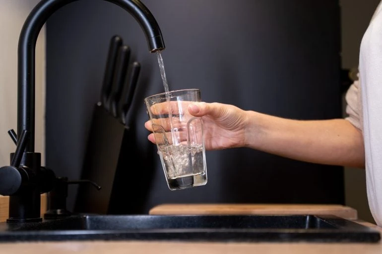 woman filling glass with tap water