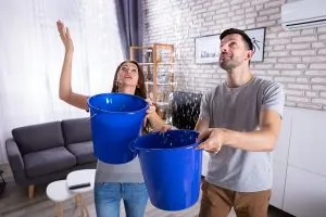 husband wife with buckets during ceiling leak